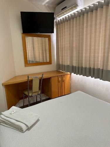 a bedroom with a bed and a desk and a television at Condall Palace Hotel in Nova Prata