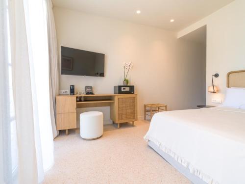 a bedroom with a bed and a desk with a television at Argostoli Essence Suites in Argostoli