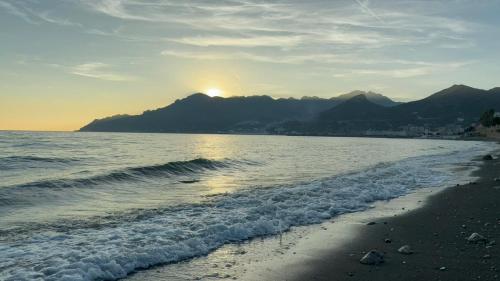 a beach with the sun setting behind a mountain at STELLA MARIUS in Salerno
