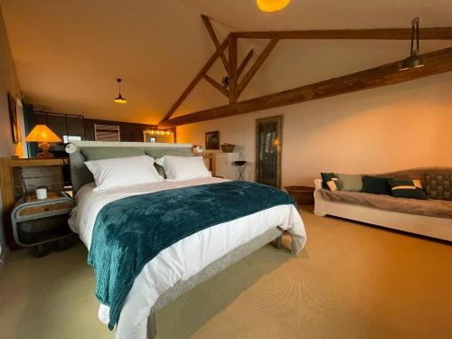 - une chambre avec un grand lit et un canapé dans l'établissement La Grange aux hirondelles - appartement complet et indépendant, à Commelle-Vernay