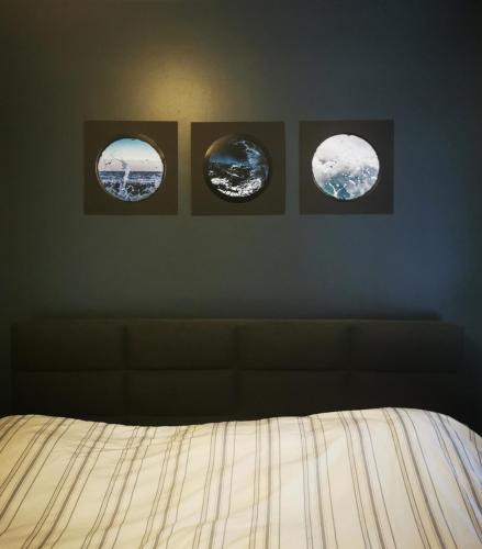 tres lienzos lunares en una pared sobre una cama en Haugesund centrum apartment en Haugesund