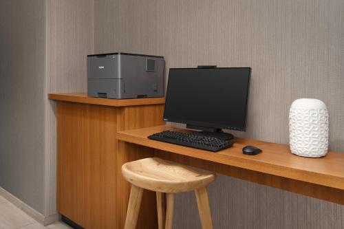 a desk with a computer monitor and a stool at SpringHill Suites By Marriott Charleston Airport & Convention Center in Charleston