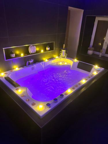 Una gran bañera púrpura con luces en el baño. en Maison Le Nid des Cigognes balnéothérapie pour 2, en Oberbronn