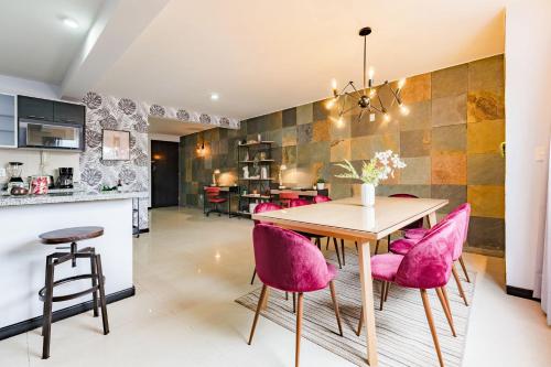 a kitchen and dining room with a wooden table and pink chairs at NEW Great Stay in Roma 24-7 Security in Mexico City