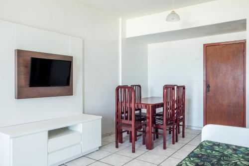 a dining room with a table and chairs and a tv at Apart Hotel Porto Príncipe in Cabo Frio