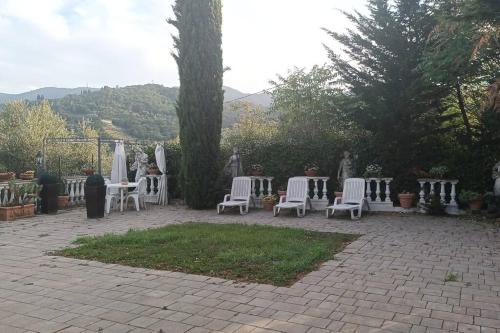 grupa białych krzeseł i stołów na patio w obiekcie Casa tranquilla colonica toscana vicino a Firenze w mieście Seano