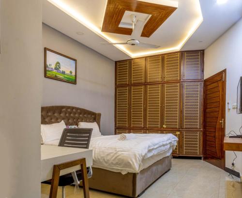 a bedroom with a bed and a desk and a window at Holidazzle Lodge Islamabad in Islamabad