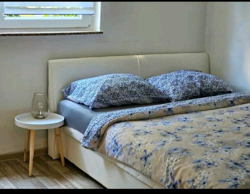 a bed with two pillows on it with a table at Oaza mira in Osijek