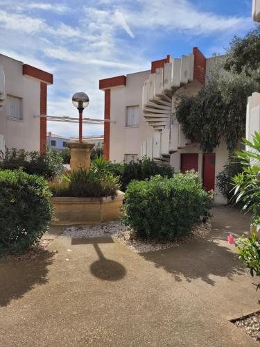 a courtyard of a building with a fountain and bushes at Tahiti Beach, T2 à la mer, piscine, terrasse et parking in Frontignan