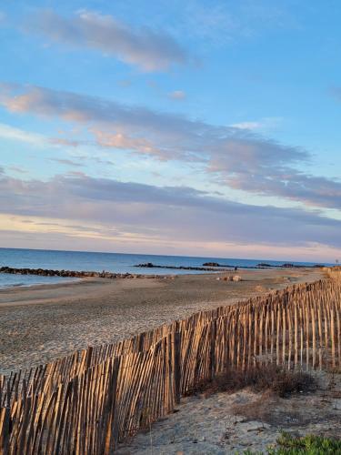 a wooden fence on a beach near the ocean at Tahiti Beach, T2 à la mer, piscine, terrasse et parking in Frontignan