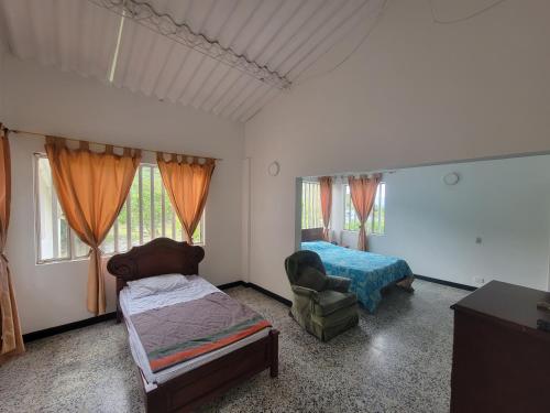 1 dormitorio con cama, silla y ventana en Finca Margaritas, en Sasaima