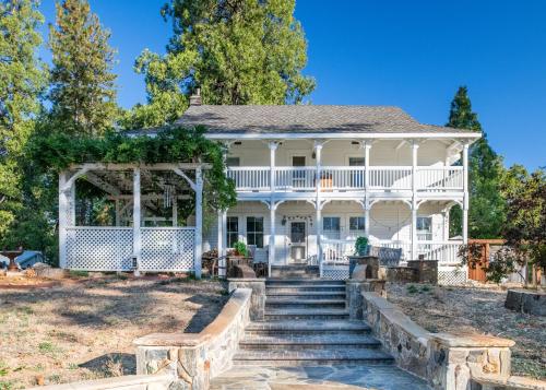 una antigua casa blanca con porche y escaleras en Inn at Sugar Pine Ranch, en Groveland