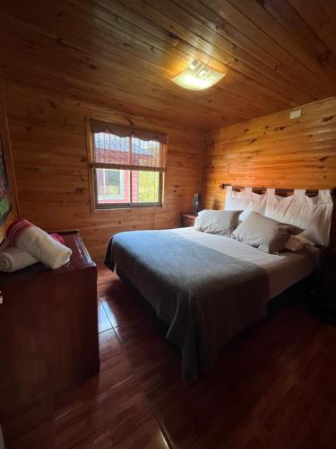 ein Schlafzimmer mit einem Bett in einer Holzhütte in der Unterkunft Cabañas Rukaparra in Pinto