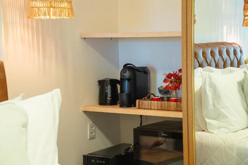 Pousada Mansão da Costa في ماراغوغي: غرفة مع سرير مع آلة صنع القهوة على رف