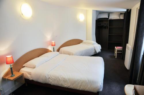 a hotel room with two beds and a closet at Hotel de la Tour in Paris