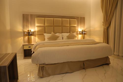 a bedroom with a large white bed with two lamps at روز نجد للشقق الفندقية in Riyadh