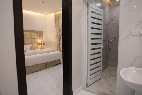 a bedroom with a bed and a bathroom with a sink at روز نجد للشقق الفندقية in Riyadh