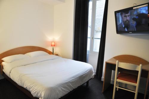 a bedroom with a bed and a tv on the wall at Hotel de la Tour in Paris