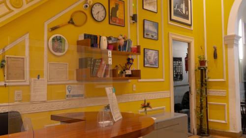 Zimmer mit gelber Wand, Tisch und Uhren in der Unterkunft Sevilla Home Hotel in Buenos Aires