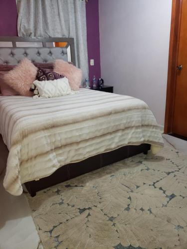 um quarto com uma cama com um cobertor e um tapete em cabaña mariposa monarca em Mineral de Angangueo