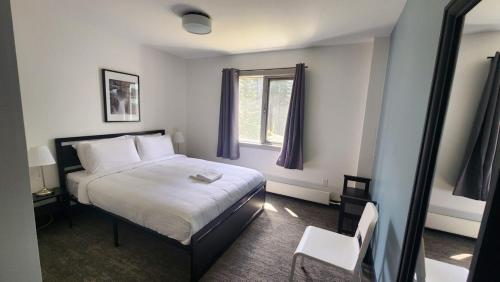 a bedroom with a white bed and a window at HI Lake Louise Alpine Centre - Hostel in Lake Louise