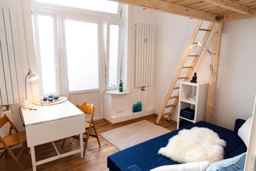 Habitación con cama, escritorio y escalera. en Grindelzimmer, en Hamburgo