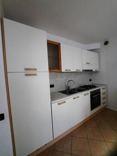 a kitchen with white cabinets and a white refrigerator at Appartamento Torrefranca in Trento