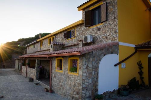 un edificio con una fachada de piedra con el sol detrás. en L'Aquila, en Arbus