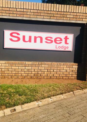 a sign for a sun set lodge on a brick wall at Kganya@Sunset Lodge in Phalaborwa