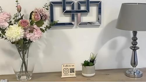 a table with a vase of flowers and a lamp at Central penthouse by HNFC Stays in Newcastle upon Tyne
