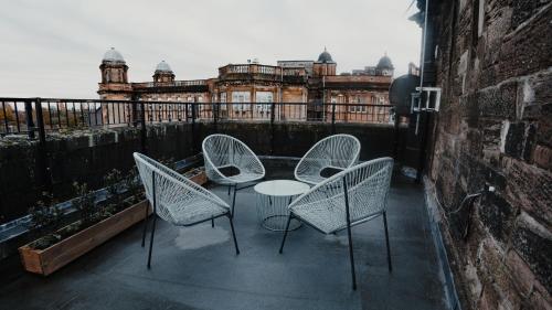 um pátio com 3 cadeiras e uma mesa na varanda em Royal Chambers Serviced Apartments em Glasgow