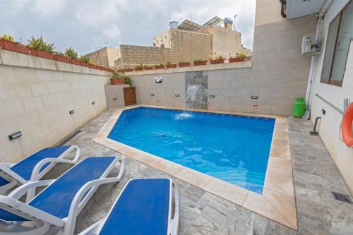una piscina con sedie e un edificio sullo sfondo di 5 Bedroom Holiday Home with Private Pool a Xewkija