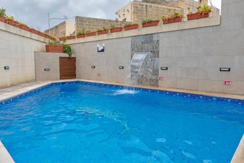 una piscina con una cascada en el lateral de un edificio en 5 Bedroom Holiday Home with Private Pool, en Xewkija