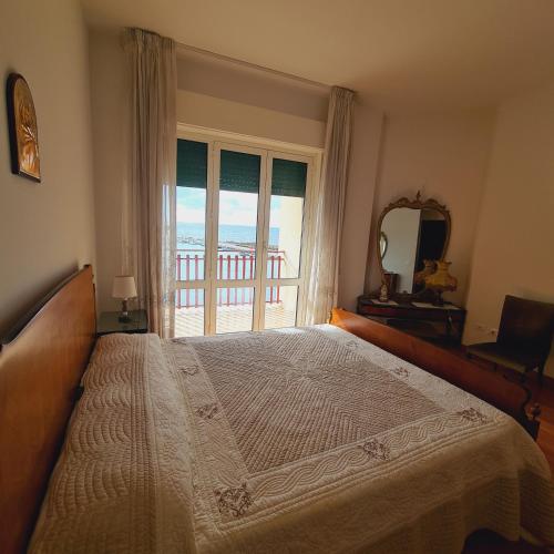 a bedroom with a large bed and a large window at Un Letto sul Mare (vit vit vit) in Marsala