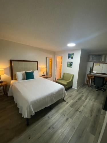 a bedroom with a large white bed and a chair at American Inn in Pensacola