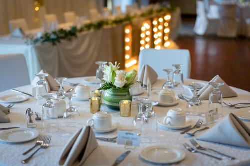 a table with a white table cloth with silverware and flowers at Best Western Inn On The Bay in Owen Sound