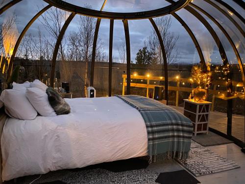 Cottage with Glass Bubble and Hot tub في ريكهولت: غرفة نوم بسرير في شرفة