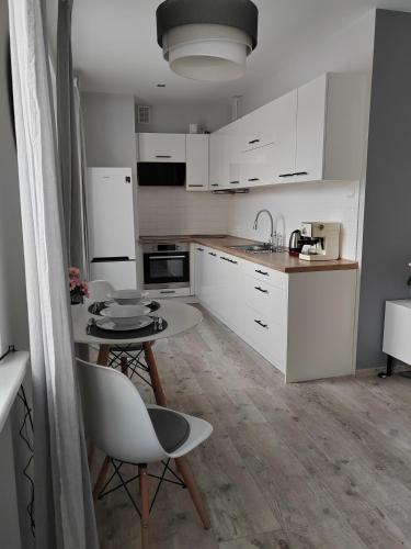 Una cocina con gabinetes blancos y una mesa y sillas. en Apartament Paderewskiego, en Kielce
