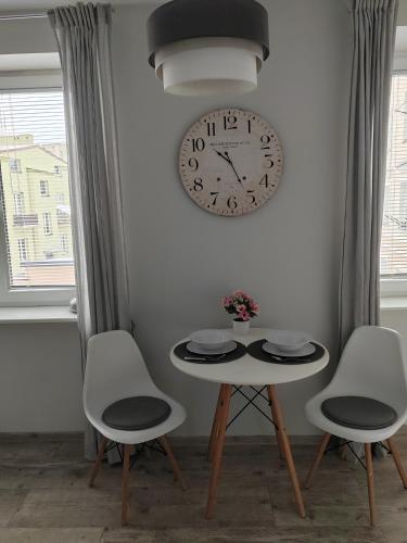 una mesa con dos sillas y un reloj en la pared en Apartament Paderewskiego, en Kielce