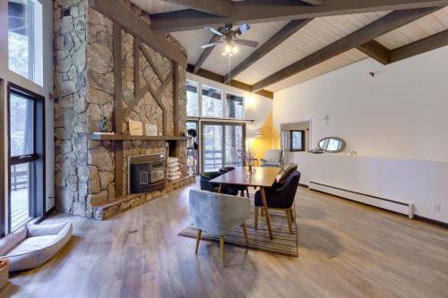 uma sala de estar com uma mesa e uma lareira de pedra em Mid-Century Cabin Creekside, Easy Access to i-70 em Dumont