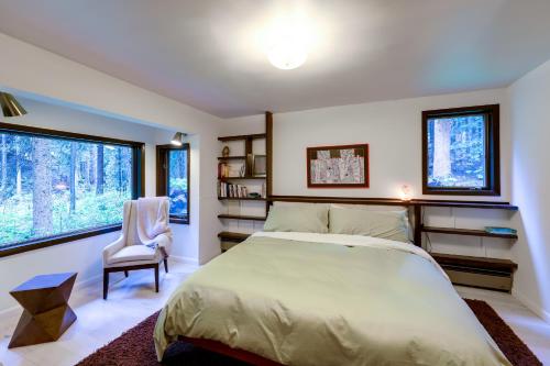 ein Schlafzimmer mit einem Bett und einem Stuhl sowie zwei Fenstern in der Unterkunft Mid-Century Cabin Creekside, Easy Access to i-70 in Dumont