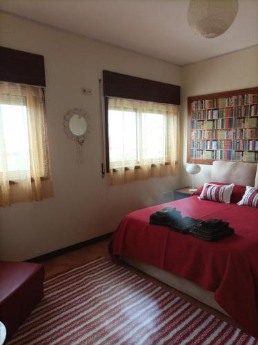 a bedroom with a bed with a red blanket and windows at Yellow House in Senhora da Hora