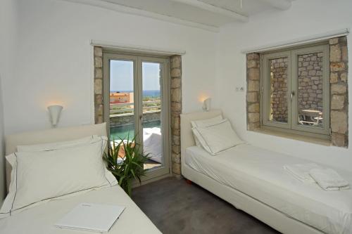 ein weißes Zimmer mit zwei Betten und einem Fenster in der Unterkunft Vista Mare Villas in Xerokampos