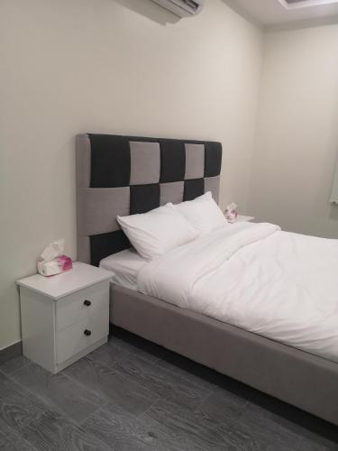 a bed with a black and white headboard and a night stand at هلتون بلو in Makkah