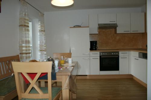 una cocina con armarios blancos y una mesa con una silla en Ferienwohnungen Hollerberg Wohnung 1, en Regen