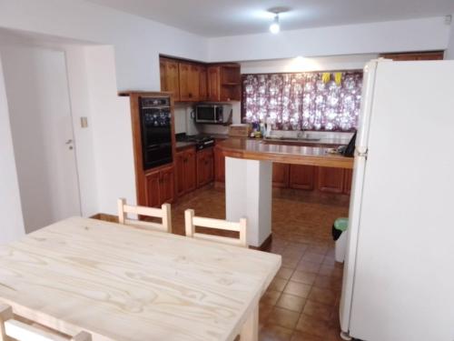 eine Küche mit einem Holztisch und einem weißen Kühlschrank in der Unterkunft Casa grande en Mar del Plata, cochera, parrilla, parque, TV con wifii. IMPECABLE in Mar del Plata