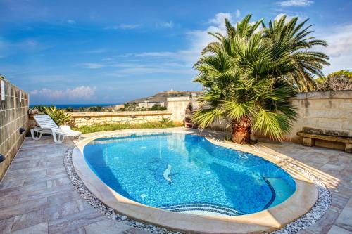 a swimming pool on a patio with a palm tree at 5 Bedroom Farmhouse with Private Pool & Views in Għarb
