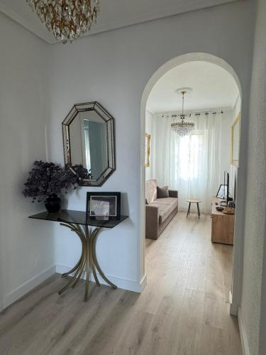 a living room with a table and a mirror at Bajo con terraza a 5 min de la playa (3 hab-6 per) in Santander