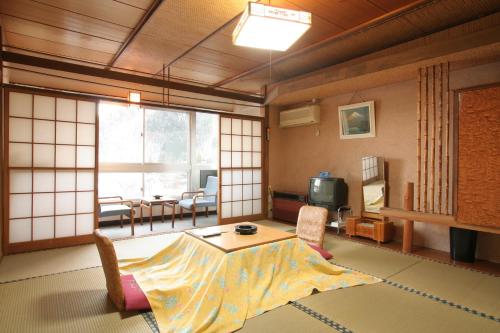 a living room with a table and a tv in a room at Yamadaya Hotel in Fujikawaguchiko