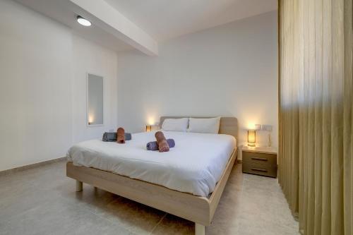 ein Schlafzimmer mit einem großen Bett mit zwei Schuhen darauf in der Unterkunft Valley's Edge Apartments in San Ġwann